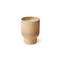Beige ceramic cup with candle just visible on a white background