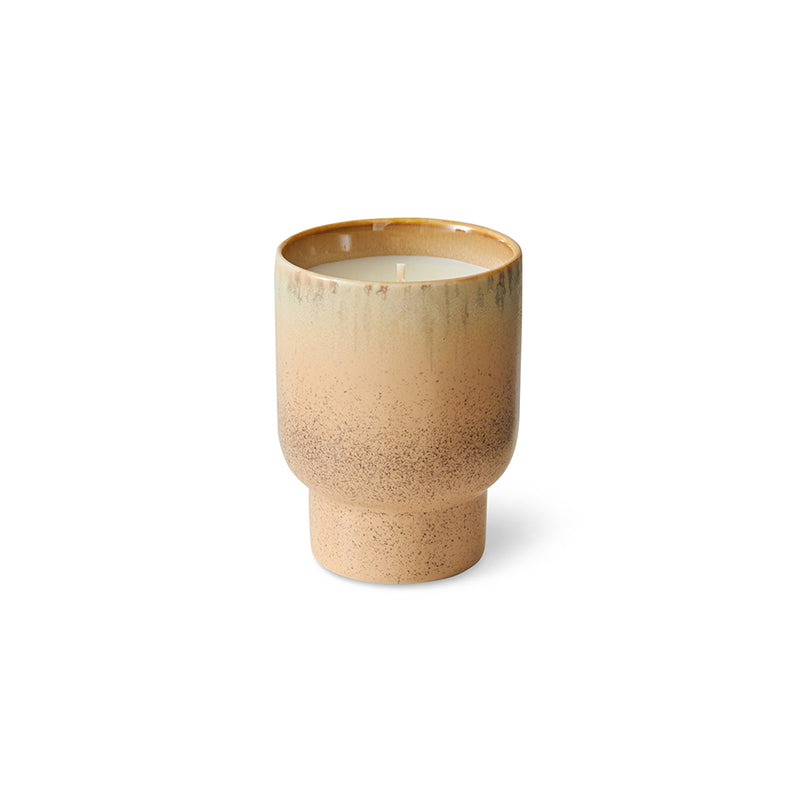 Beige ceramic cup with candle just visible on a white background