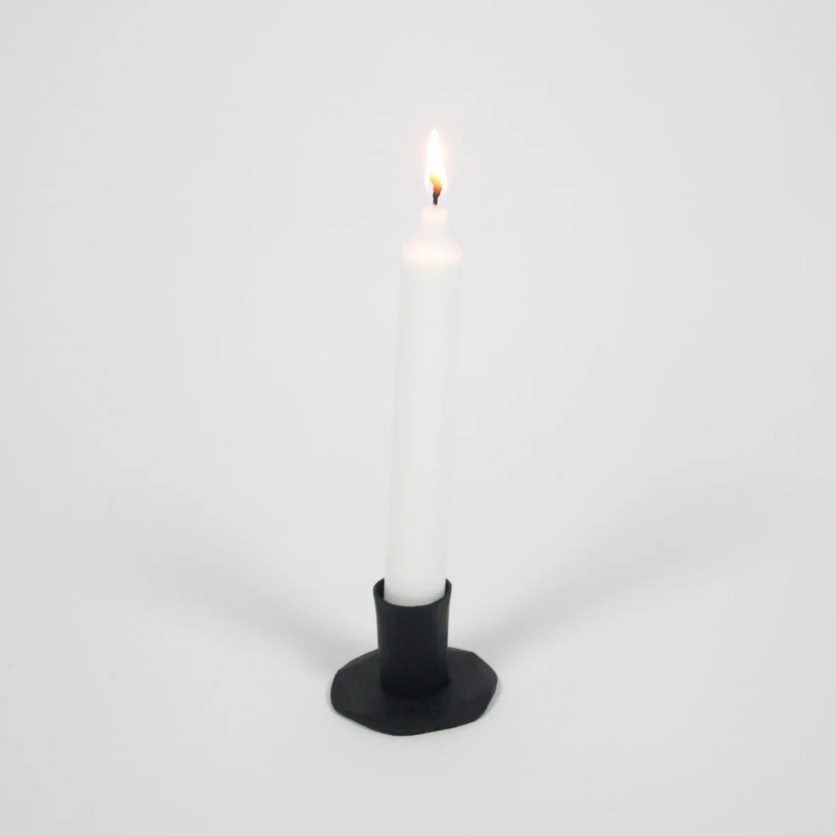 Adrian short black iron candle holder by Olsson & Jensen with a white taper candle
