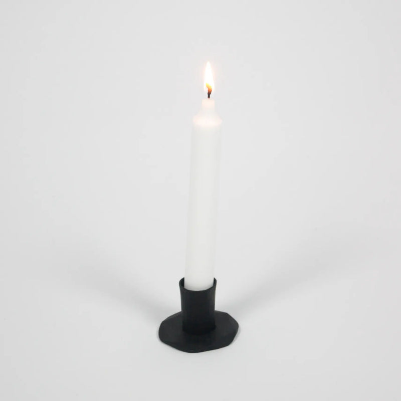 Adrian short black iron candle holder by Olsson & Jensen with a white taper candle