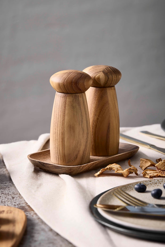 Wooden salt and pepper shakers on a tray with a neutral background