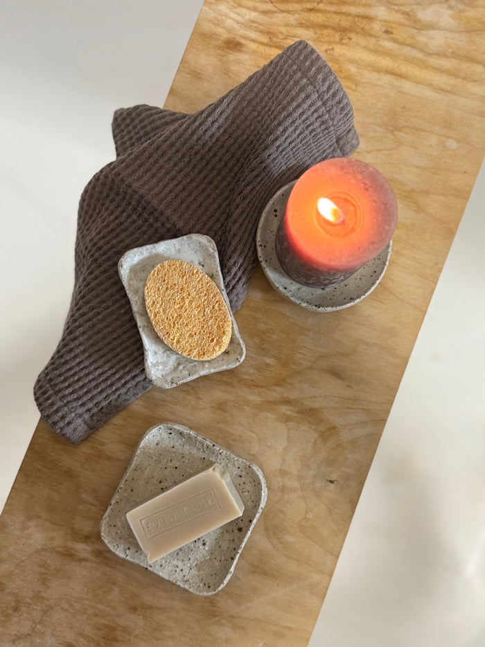 Bar of soap, sponge, and candle on a wooden surface