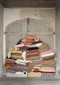 stacked velvet and patterned cushions including burnt orange bolster in rustic Scandinavian interior
