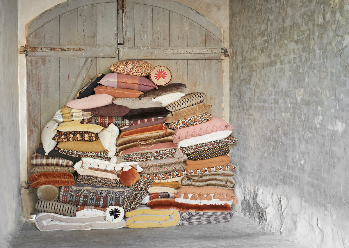 mix of autumn-toned cushions with burnt orange bolster styled in vintage interior setting
