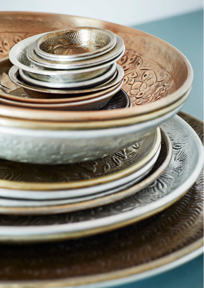 stack of hand-hammered brass and aluminium dishes in layered textured finish
