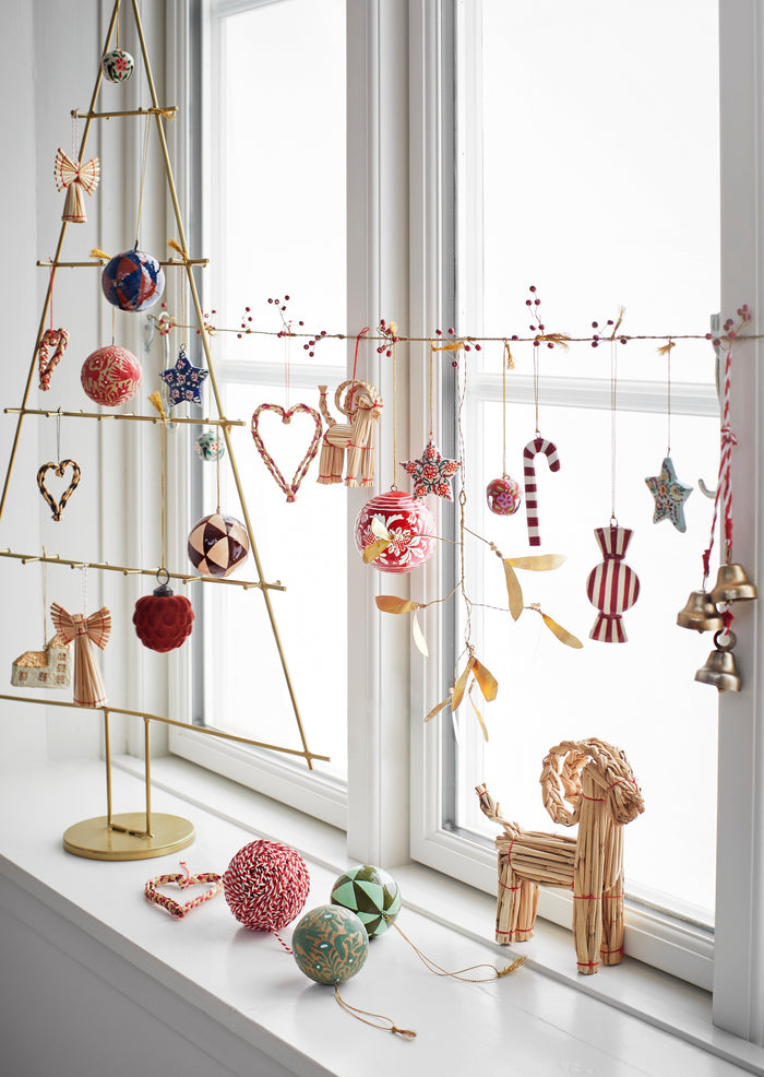 Scandinavian Christmas display with brass hanging bells and red-and-white string
