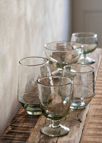 clear hammered glass dessert cups arranged together on a wooden shelf
