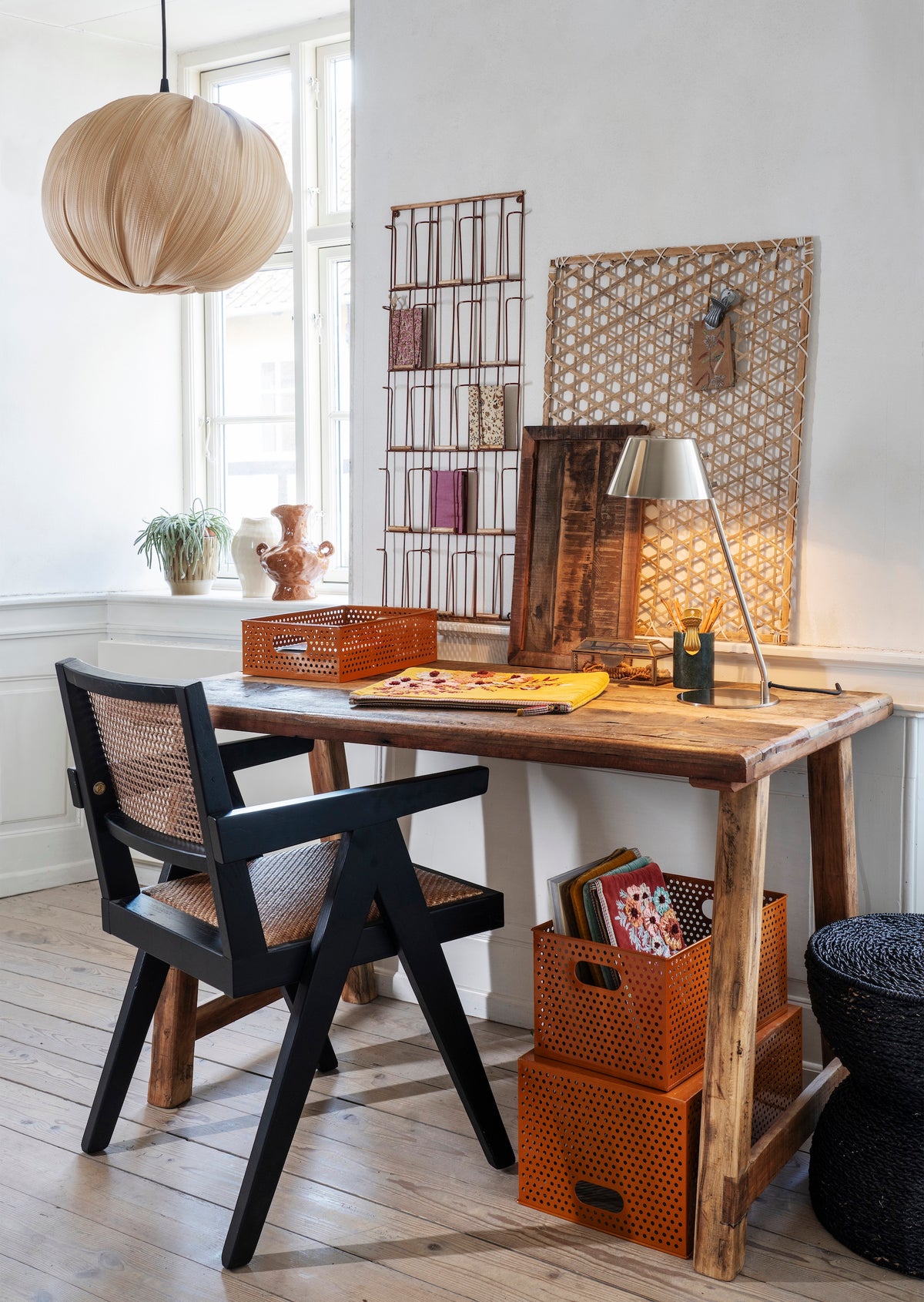 Wooden desk with black chair in a room with decorative elements.