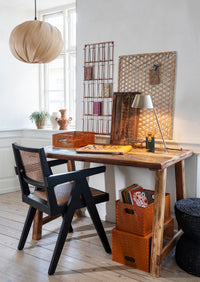 Wooden desk with black chair in a room with decorative elements.