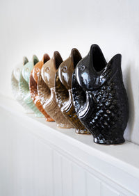 stoneware fish vases in multiple colours including khaki and black arranged on a shelf for playful home decor
