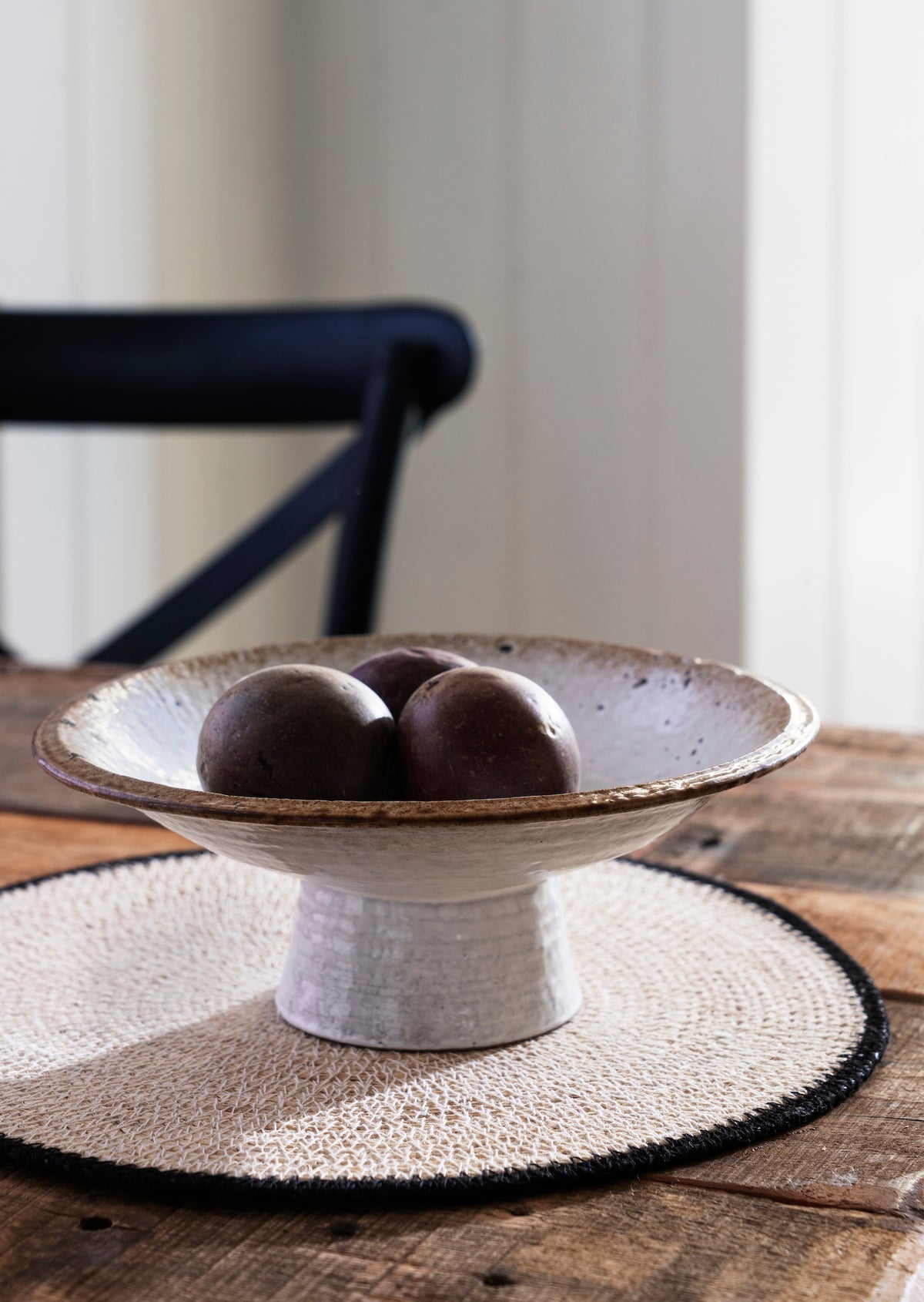White ceramic bowl with brown rim on a wooden table with a blurred background