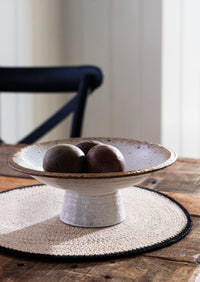 White ceramic bowl with brown rim on a wooden table with a blurred background