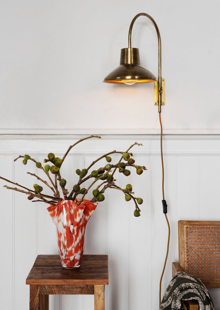 rust and white sculptural glass vase styled in a cosy living space with wall lamp
