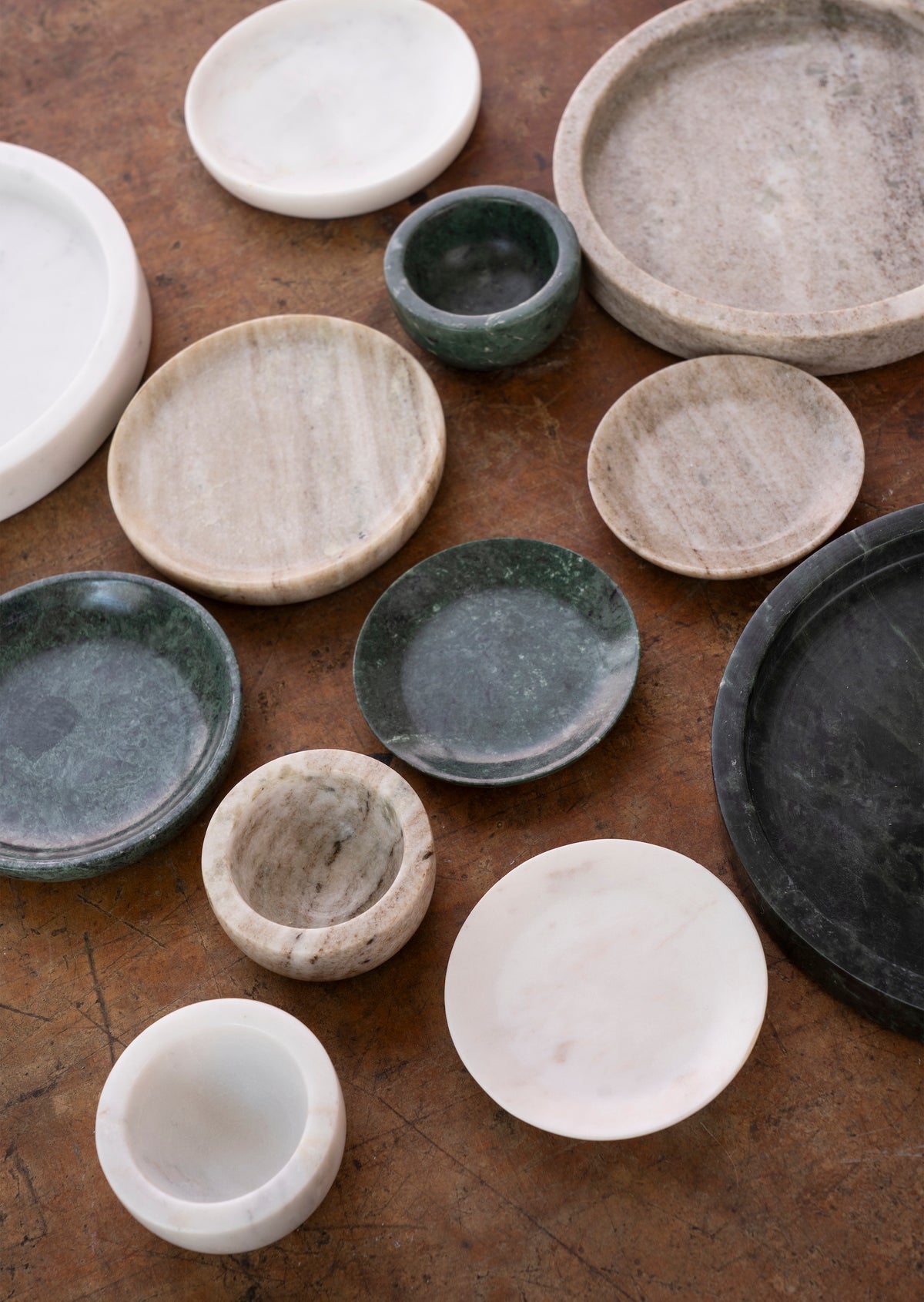 assorted white and green marble trays and bowls styled on a rustic tabletop

