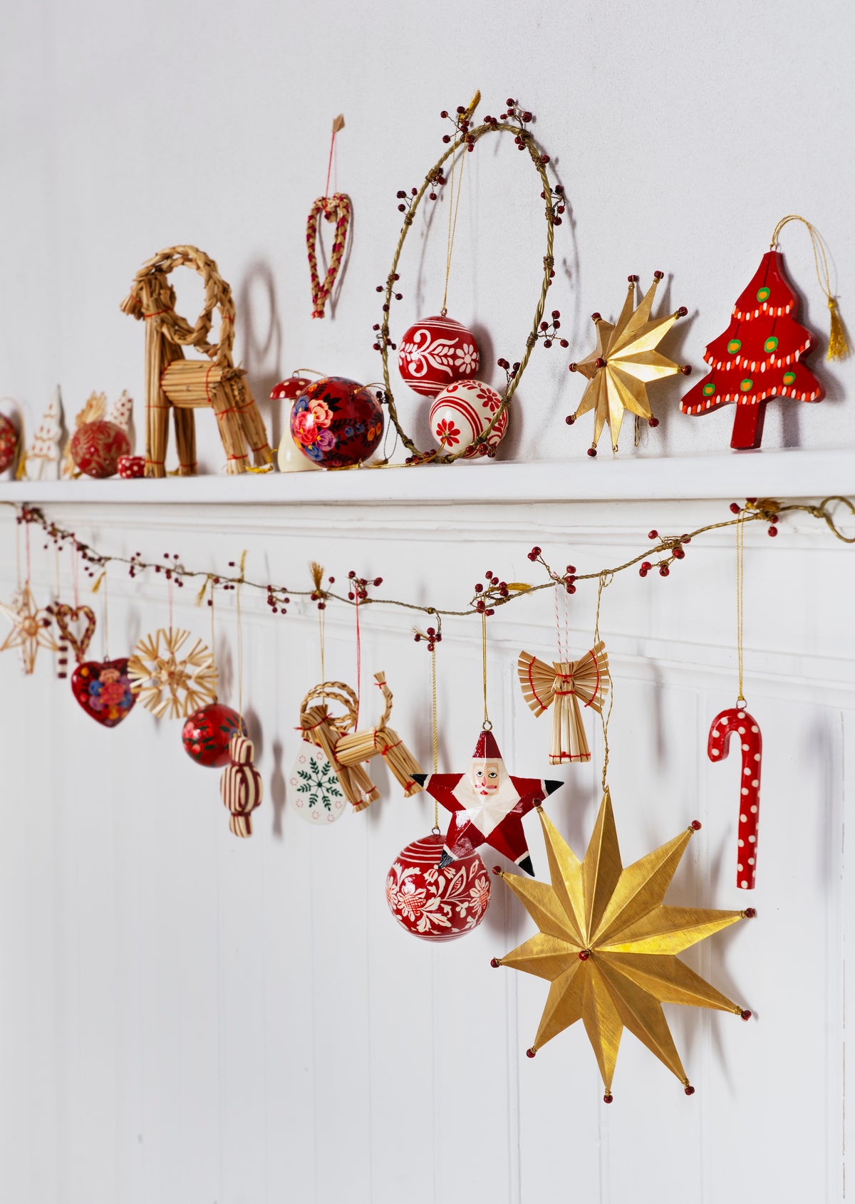 festive mantle decorated with traditional handmade ornaments including striped red paper mache candy shapes
