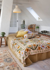 art deco wool cushion with feather filler layered with velvet and plain cushions on a bed
