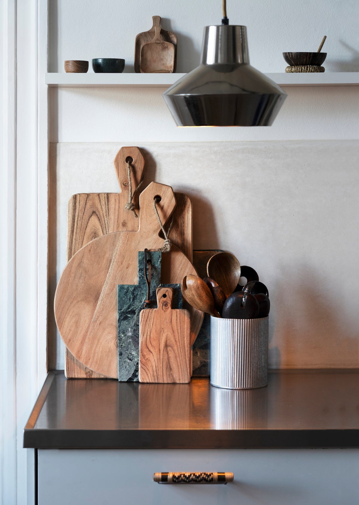 tiny wooden trays on a kitchen shelf with other rustic boards and utensils

