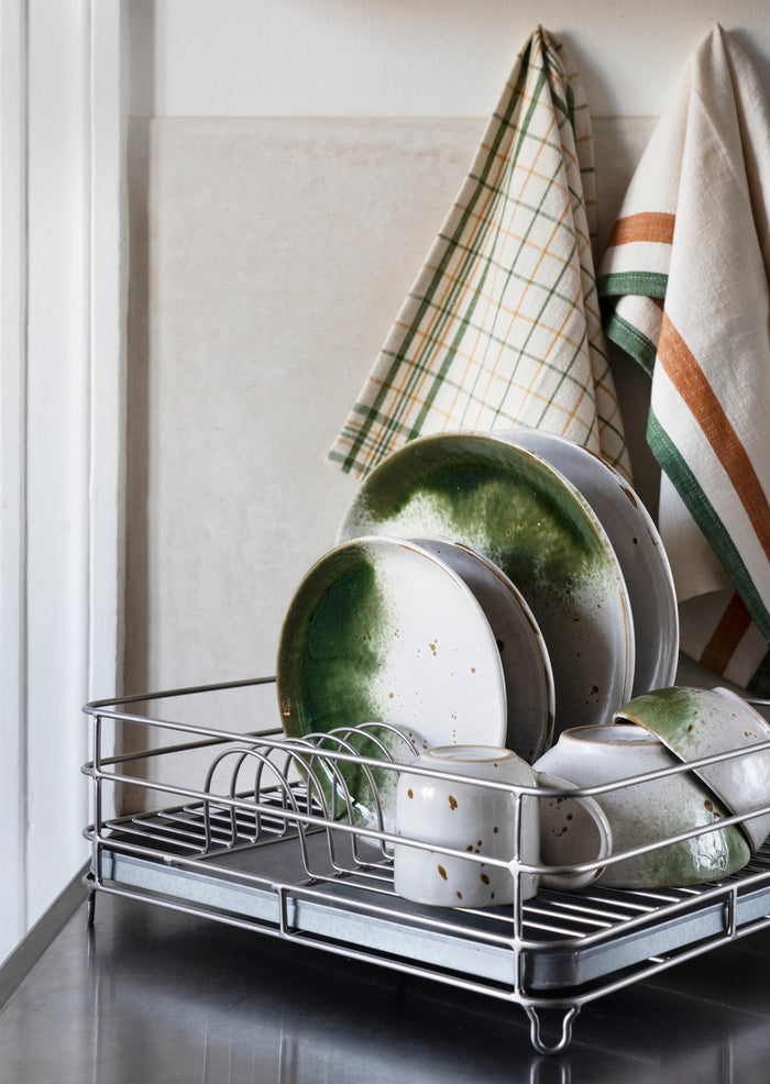 reactive glaze stoneware plates and bowls in white and green on a kitchen dish rack for relaxed Nordic style
