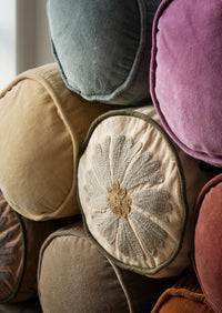 embroidered and velvet bolster cushions stacked together showing soft textures
