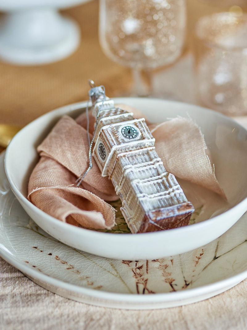 Big Ben glass Christmas ornament displayed in a ceramic bowl with soft pink napkin