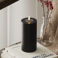 modern black LED candle with glowing flame on books for soft winter home lighting