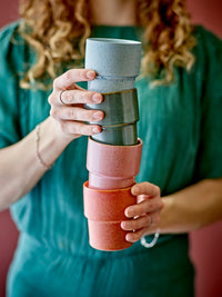 person holding stack of colourful bloomingville ewan cups showing reactive glaze
