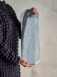 person holding long grey marble cutting board by bloomingville to show size and veining
