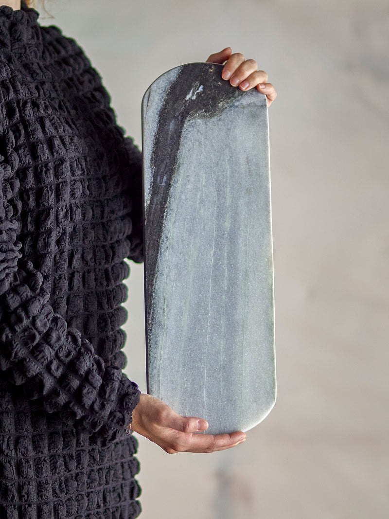 person holding long grey marble cutting board by bloomingville to show size and veining
