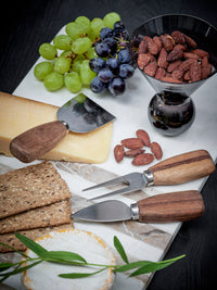 cheese board with bloomingville lisamai acacia cheese knives styled with grapes crackers and almonds
