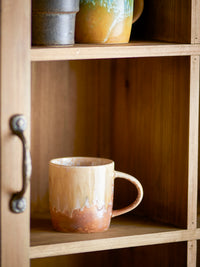 rustic stoneware milani mug in natural reactive glaze on wooden shelf
