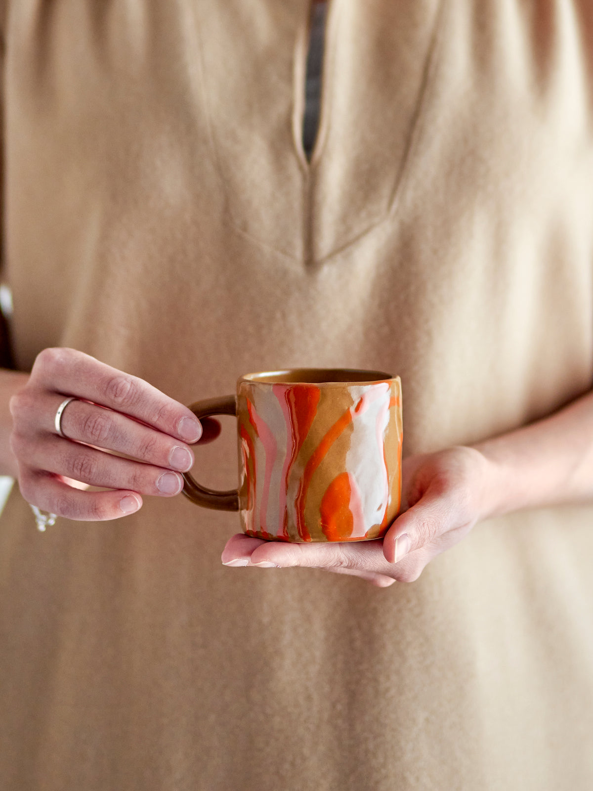 person holding orange bloomingville ninka mug showing hand-decorated glaze
