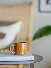orange bloomingville ninka mug styled on a book in a relaxed living room setting
