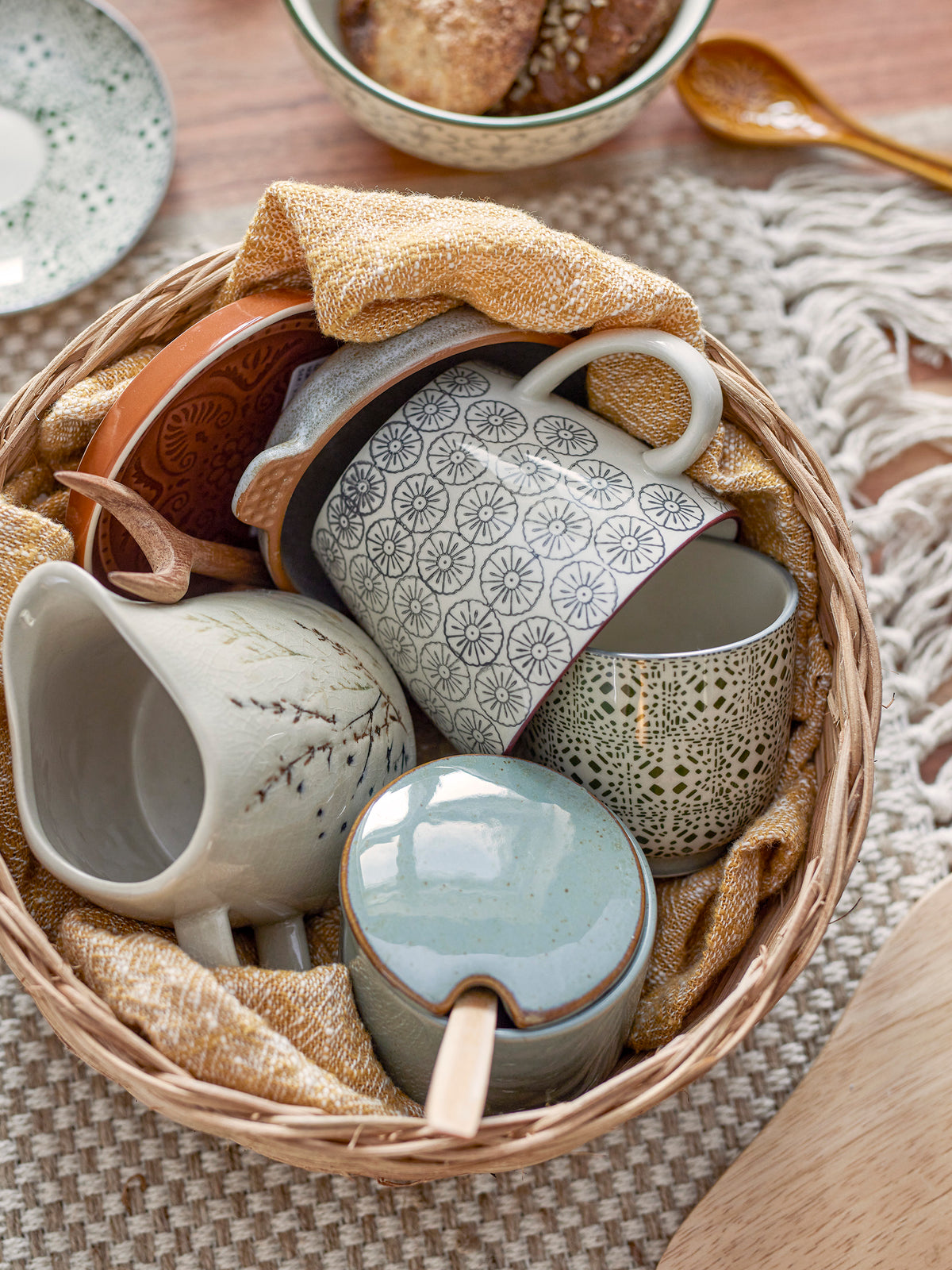 green stoneware pixie jar with wooden spoon styled in basket of cosy kitchen ceramics