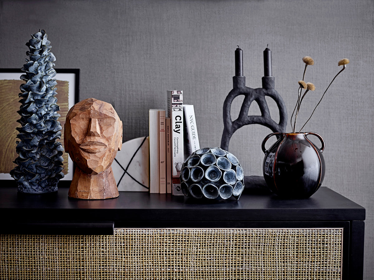 sculptural black ramina candle holder with books and ceramics on console
