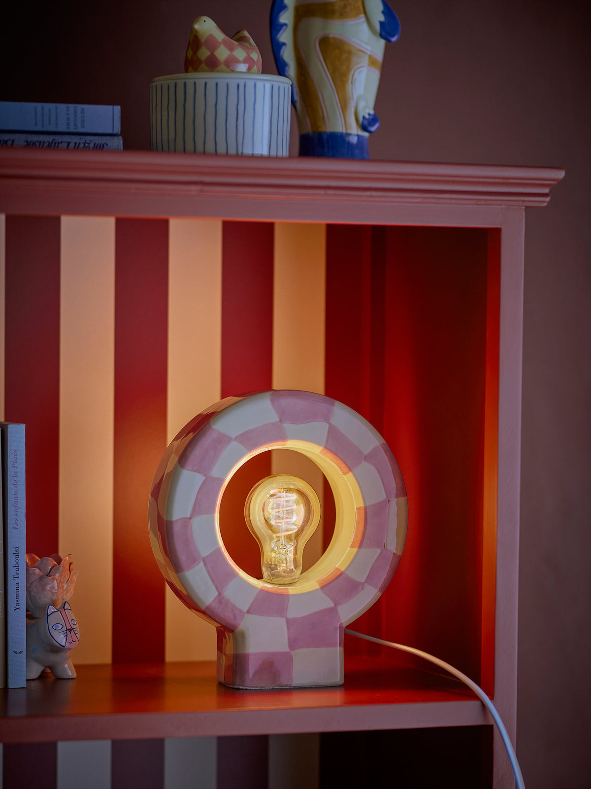 pastel pink and yellow checked stoneware bloomimgville vialini lamp styled on red striped shelf
