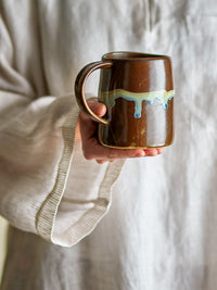 person holding brown bloomingville yori mug showing flowing reactive glaze