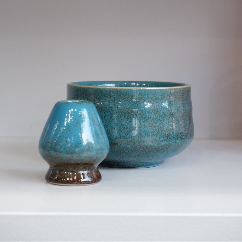 blue matcha bowl with crackle glaze and matching whisk holder styled on shelf