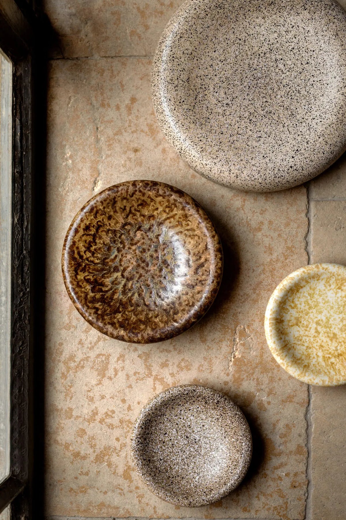 Boel speckled stoneware bowls and plates by Olsson & Jensen styled on a stone surface from above