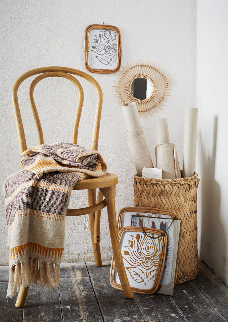 Bohemian interior with wooden chair draped in recycled cotton throw in ecru, brown and honey