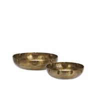 Hand-hammered brass bowl styled with textured ceramic bowls on rustic wooden surface