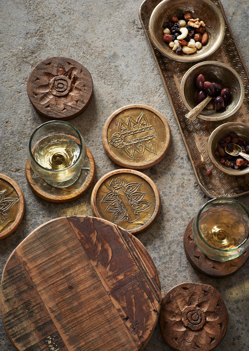 Brass spoon styled with wooden coasters and small brass bowls on a rustic table