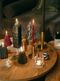 Brass Maro candle holders with red and green tapers on a festive coffee table with house-shaped candles