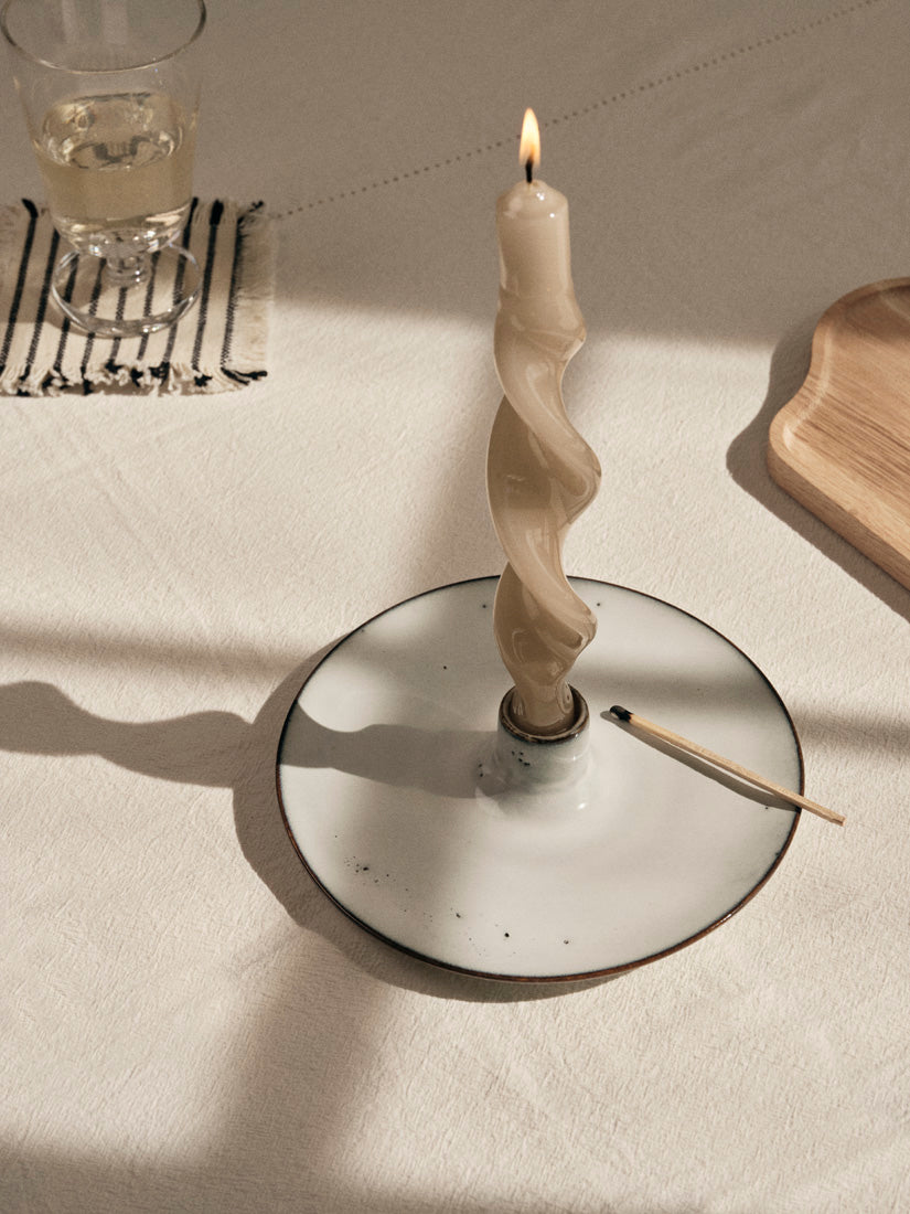 Lit cream twist candle in a Nordic Sand holder on a sunlit linen tablecloth