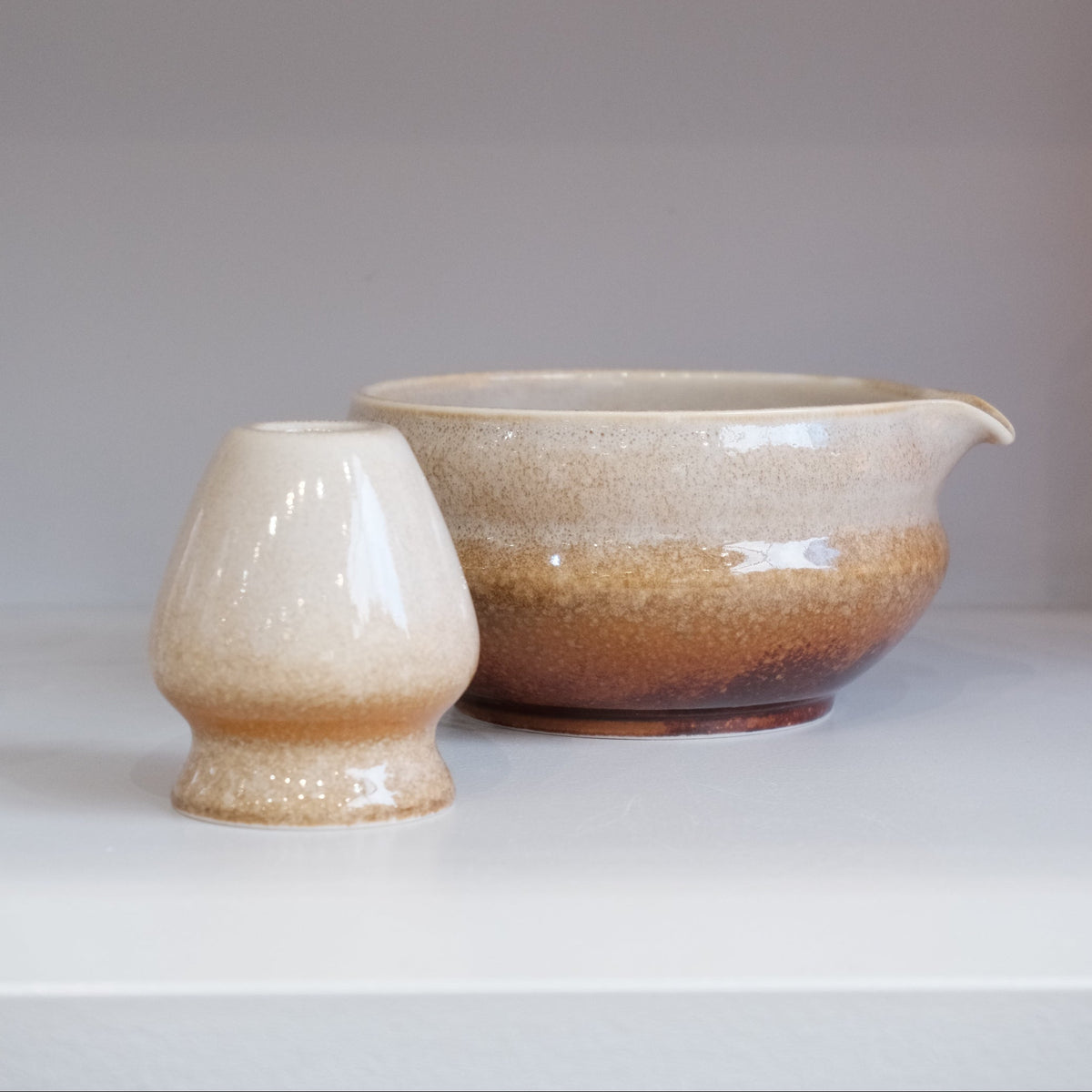 brown speckled ceramic matcha bowl with pouring spout and matching whisk stand
