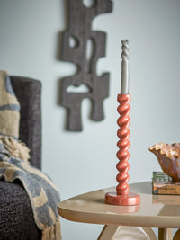 brown spiral diza candle holder with grey taper candle on side table
