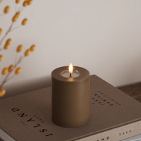 large caramel LED pillar candle with warm flame styled on coffee table for autumn ambience
