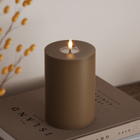caramel wax-coated LED pillar candle with warm flame styled on books for cosy autumn décor
