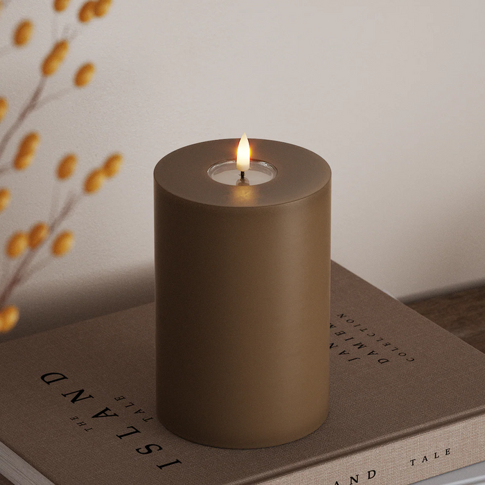 caramel wax-coated LED pillar candle with warm flame styled on books for cosy autumn décor
