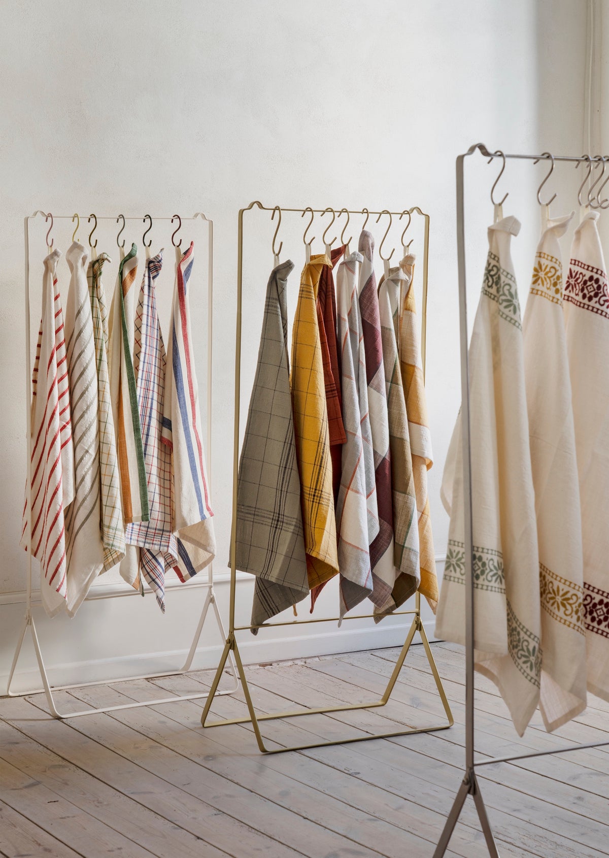 checked cotton kitchen towels in assorted colours hanging on display rack

