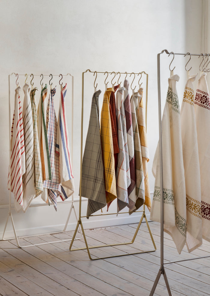checked cotton kitchen towels in assorted colours hanging on display rack
